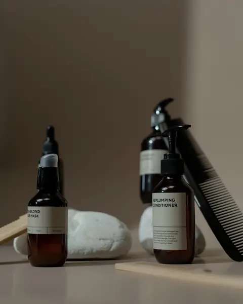 Amber bottles of hair mask and conditioner beside a black comb