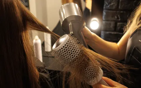 Hands blow-drying long hair over a round brush