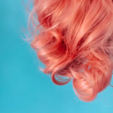 Loose coral-pink curls against a turquoise background