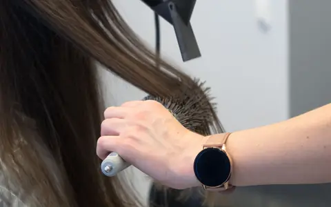 A round brush and hairdryer smoothing long brown hair