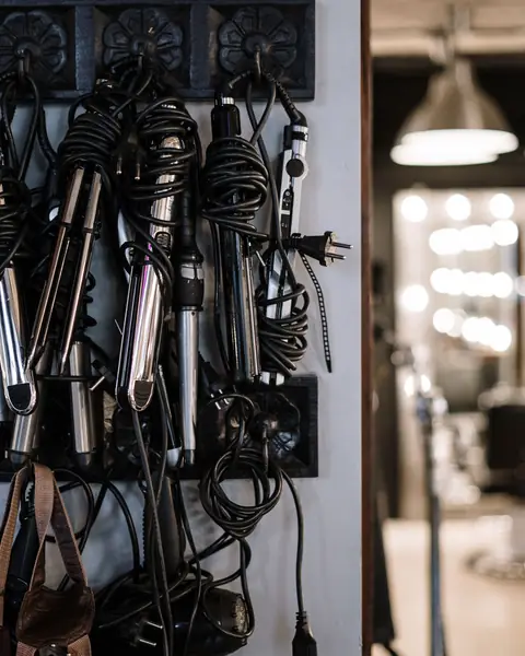 Curling irons and straighteners hanging from hooks on a salon wall